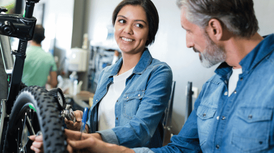 Mecánica de bicicletas y aprendiz reparando una bicicleta