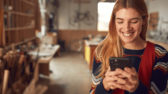 Female bicycle shop owner running payroll with the help of AI on her mobile phone.