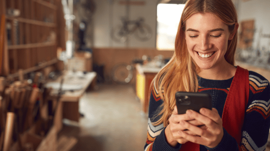 Generative AI Examples Female bicycle shop owner running payroll with the help of AI on her mobile phone.