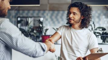 A small business owner shakes hands with a newly hired 1099 contractor.