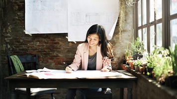 A woman sits in her office work on plans for her small business.