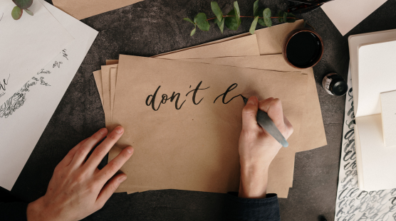 A greeting card designer writting caligraphy on a card.