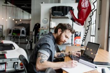 Formas más inteligentes de gestionar la nómina Propietario de un negocio concentrado en su trabajo con su laptop en un taller.