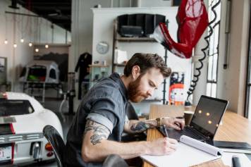 Propietario de un negocio concentrado en su trabajo con su laptop en un taller.