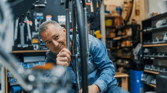 Male bike shop owner fixing a bike.