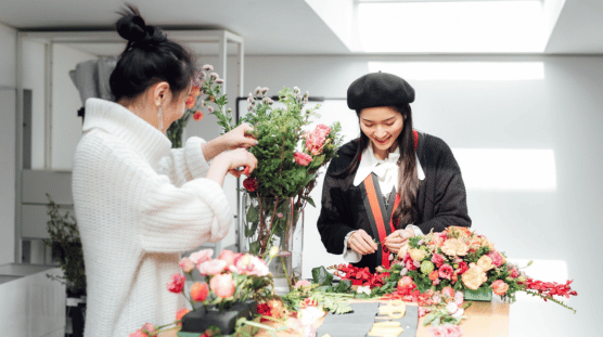A flower shop owner and her employee are making floral arrangements