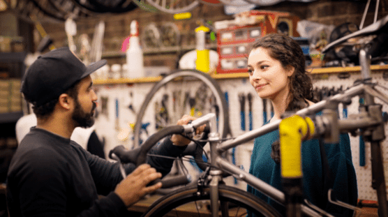 Hombre y mujer trabajando en un taller reparando una bicicleta