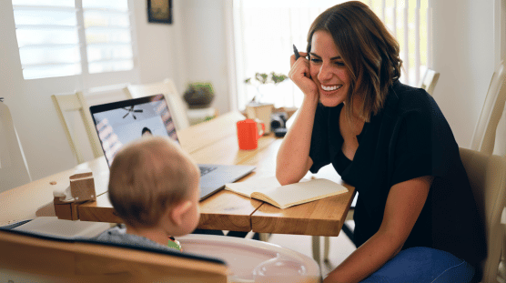 Female entrepreneur working at home and tending to her baby while on a video call.